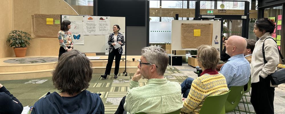 Ett tiotal män och kvinnor sitter i en halvcirkel och pratar