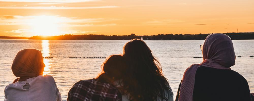 Fyra barn vända mot havet i solnedgång